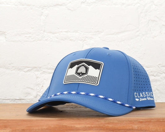 A blue baseball cap with a white rectangular patch featuring the Utah state flag engraved on the front