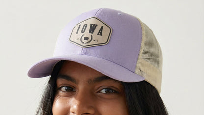 Woman wearing a purple cap with 'Iowa' logo against a plain background