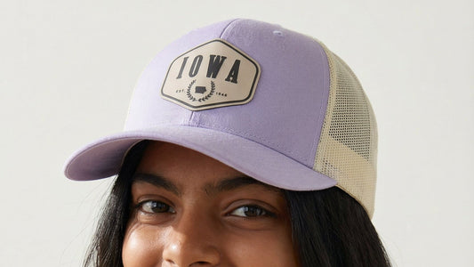 Woman wearing a purple cap with 'Iowa' logo against a plain background